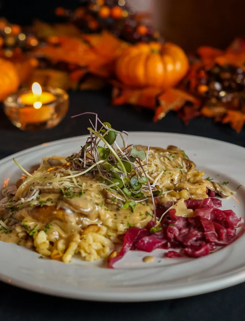 Plated chicken with creamy sauce, pasta and red cabbage on a table