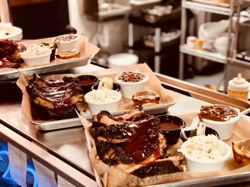 Trays of smoked ribs and sides at The Iron Pig Smokehouse