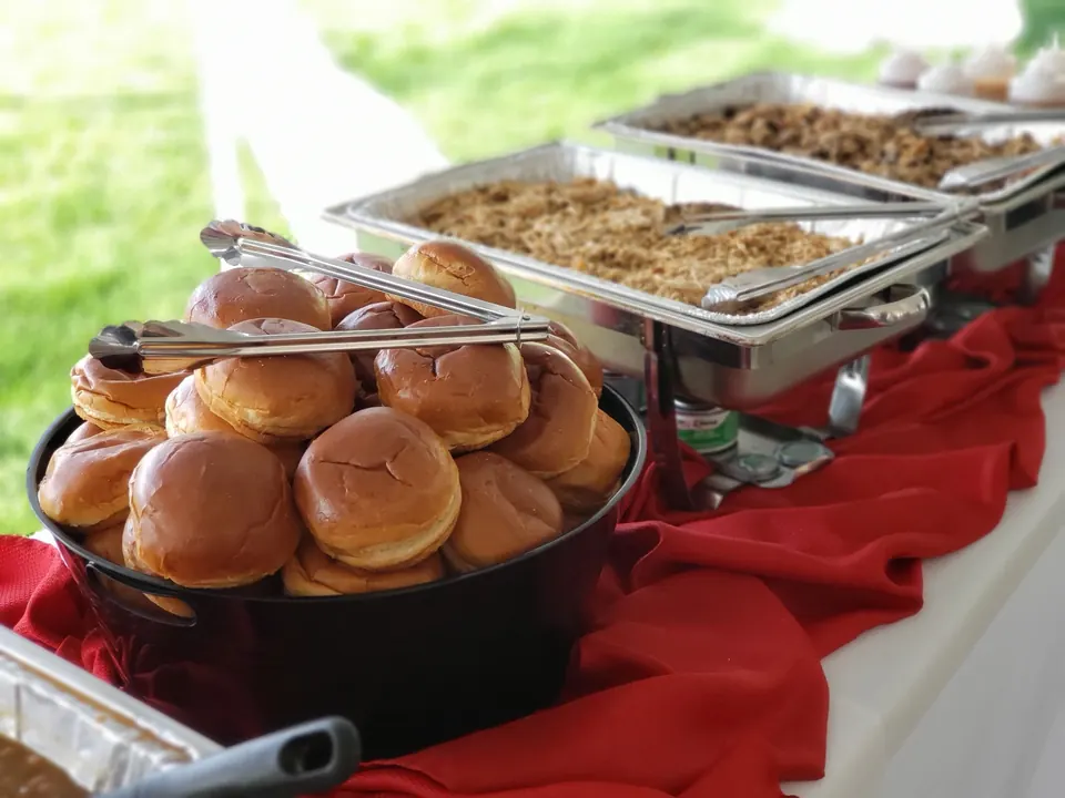 Catering spread of smoked meats, buns and sides set out for a party