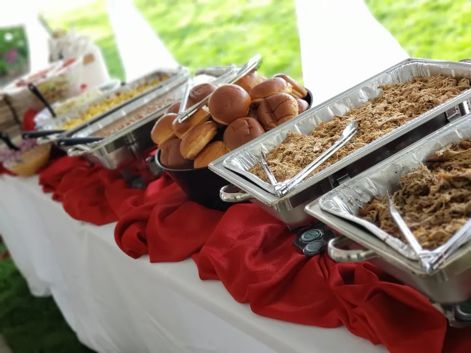 Catering buffet line with chafing dishes of smoked meats and sides