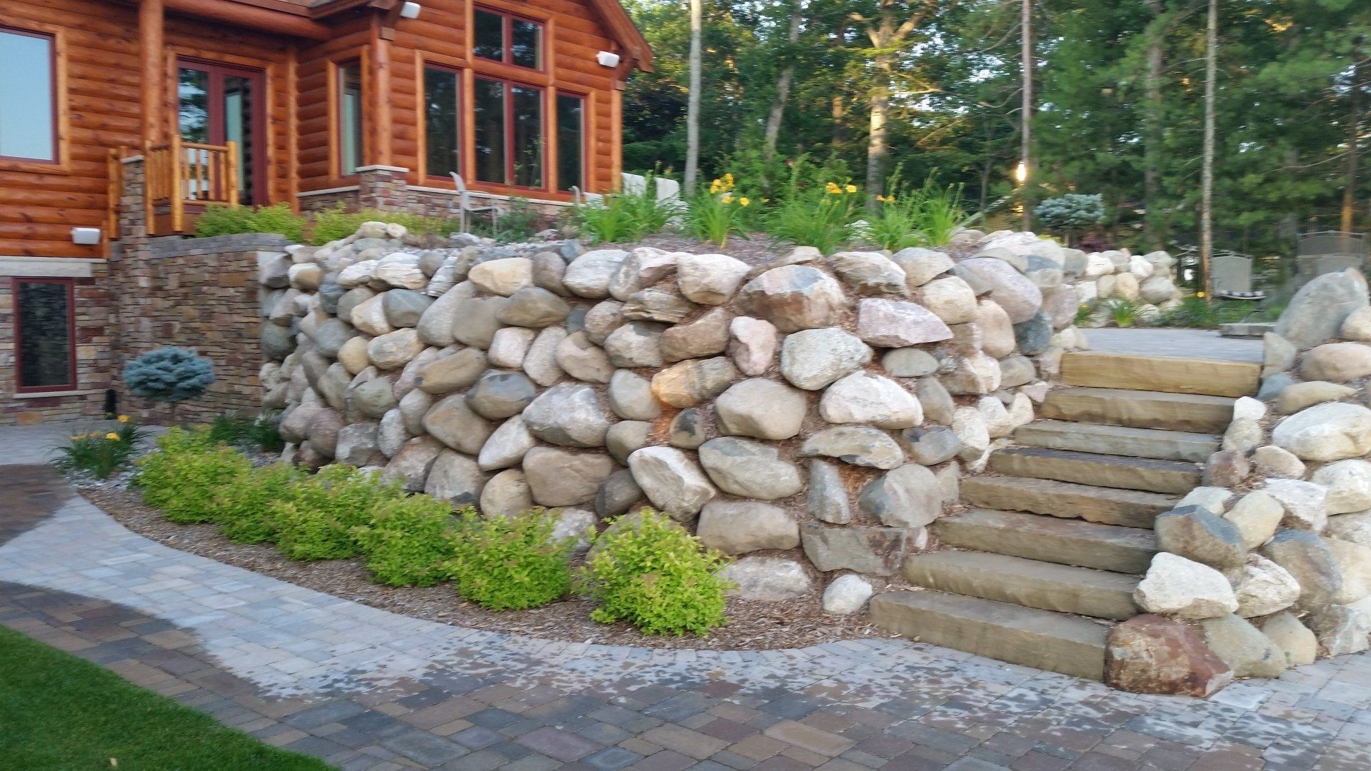 Finished pond or creek water feature in a yard, close and well lit, stone edging visible
